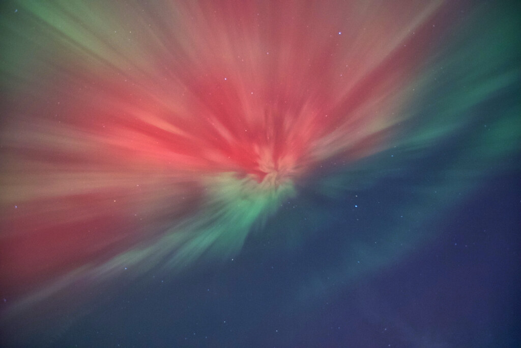 A red and green aurora corona directly overhead, rays converging at the zenith, over South Dakota